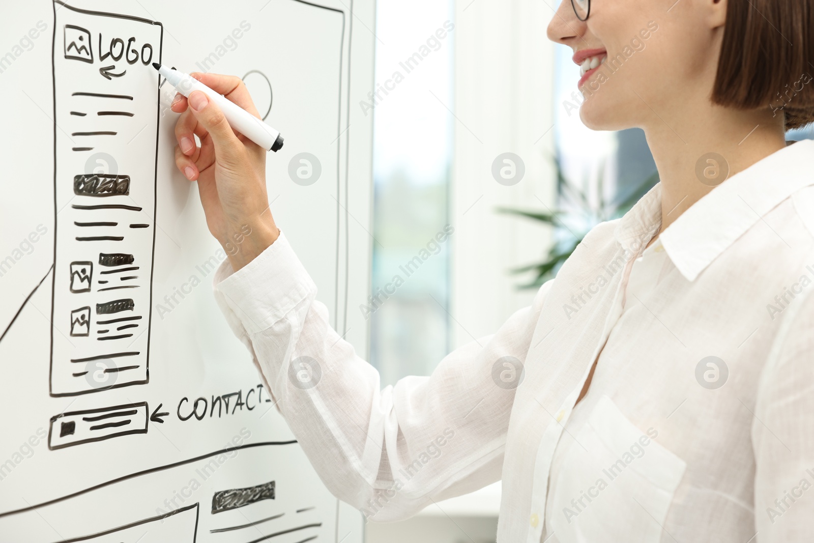 Photo of Developing UI design. Woman drawing website wireframe on whiteboard indoors, closeup