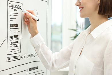 Developing UI design. Woman drawing website wireframe on whiteboard indoors, closeup