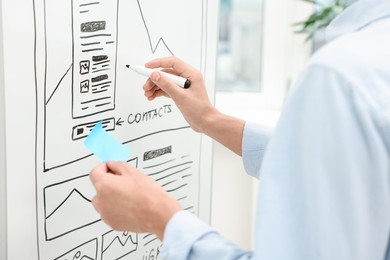 Developing UI design. Man drawing website wireframe on whiteboard indoors, closeup