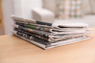 Stack of newspapers in different languages on table indoors