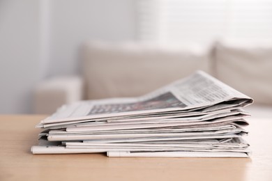 Stack of newspapers in different languages on table indoors