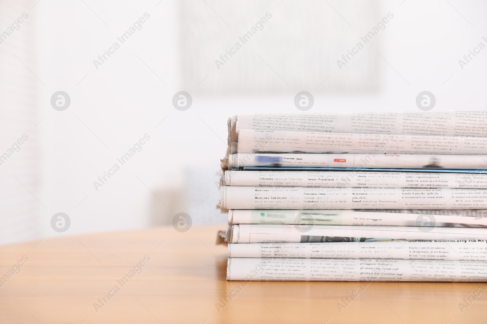 Photo of Stack of many newspapers in different languages on wooden table, space for text