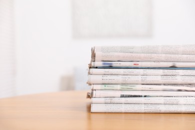 Photo of Stack of many newspapers in different languages on wooden table, space for text