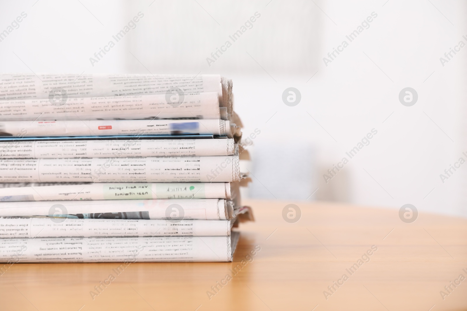 Photo of Stack of many newspapers in different languages on wooden table, space for text