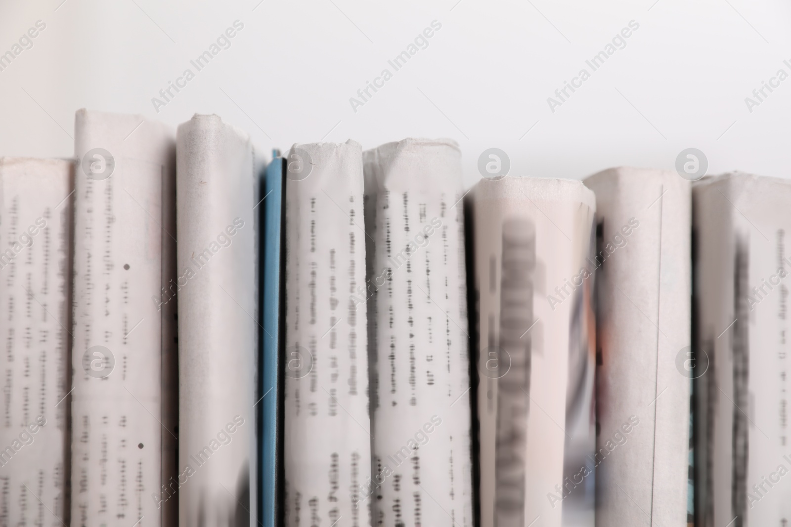 Photo of Many newspapers in different languages on blurred background, closeup