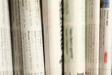 Photo of Many newspapers in different languages as background, closeup