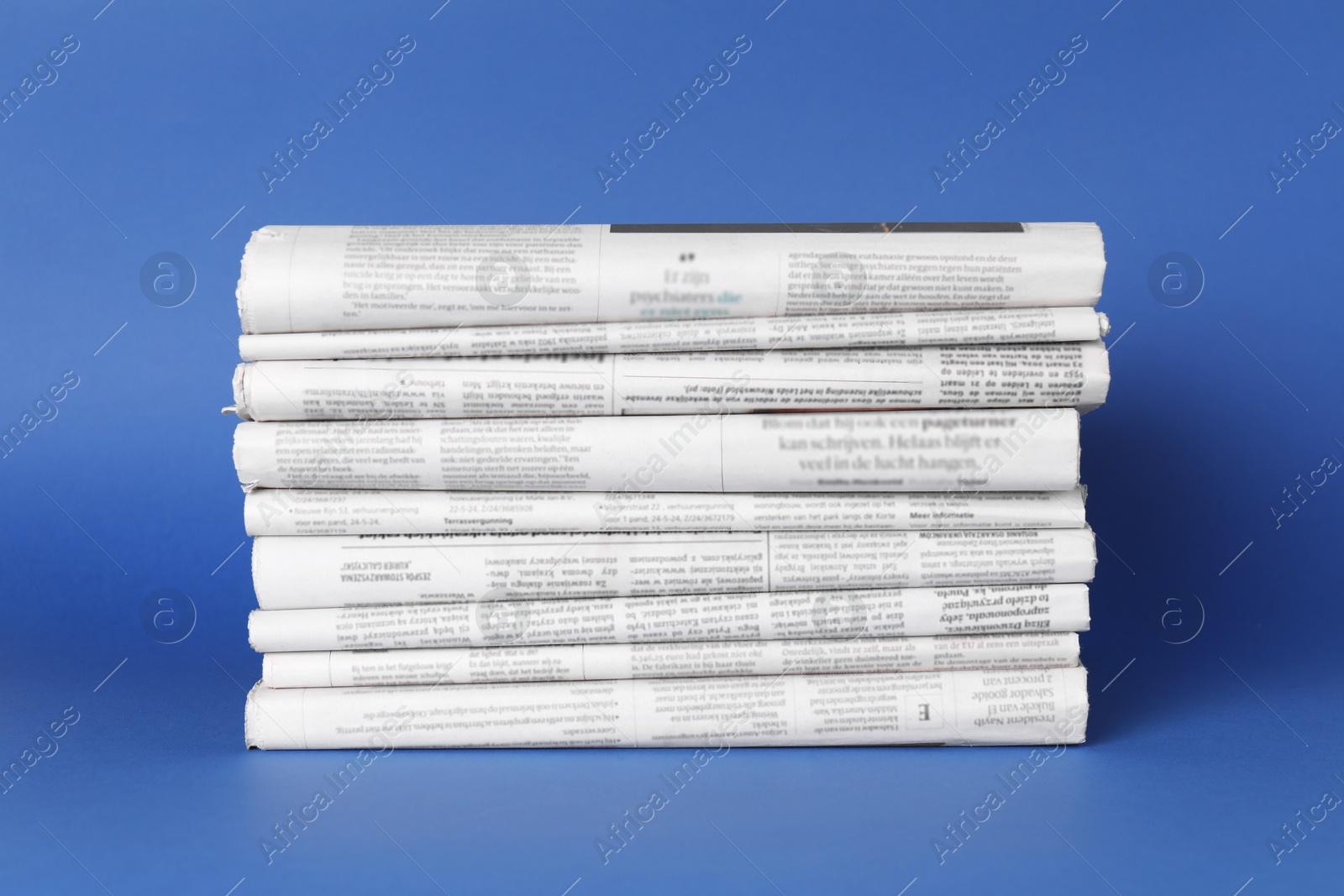 Photo of Stack of many newspapers in different languages on blue background