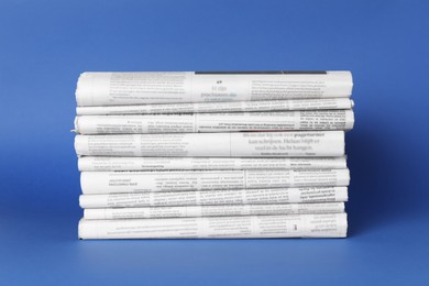 Stack of many newspapers in different languages on blue background