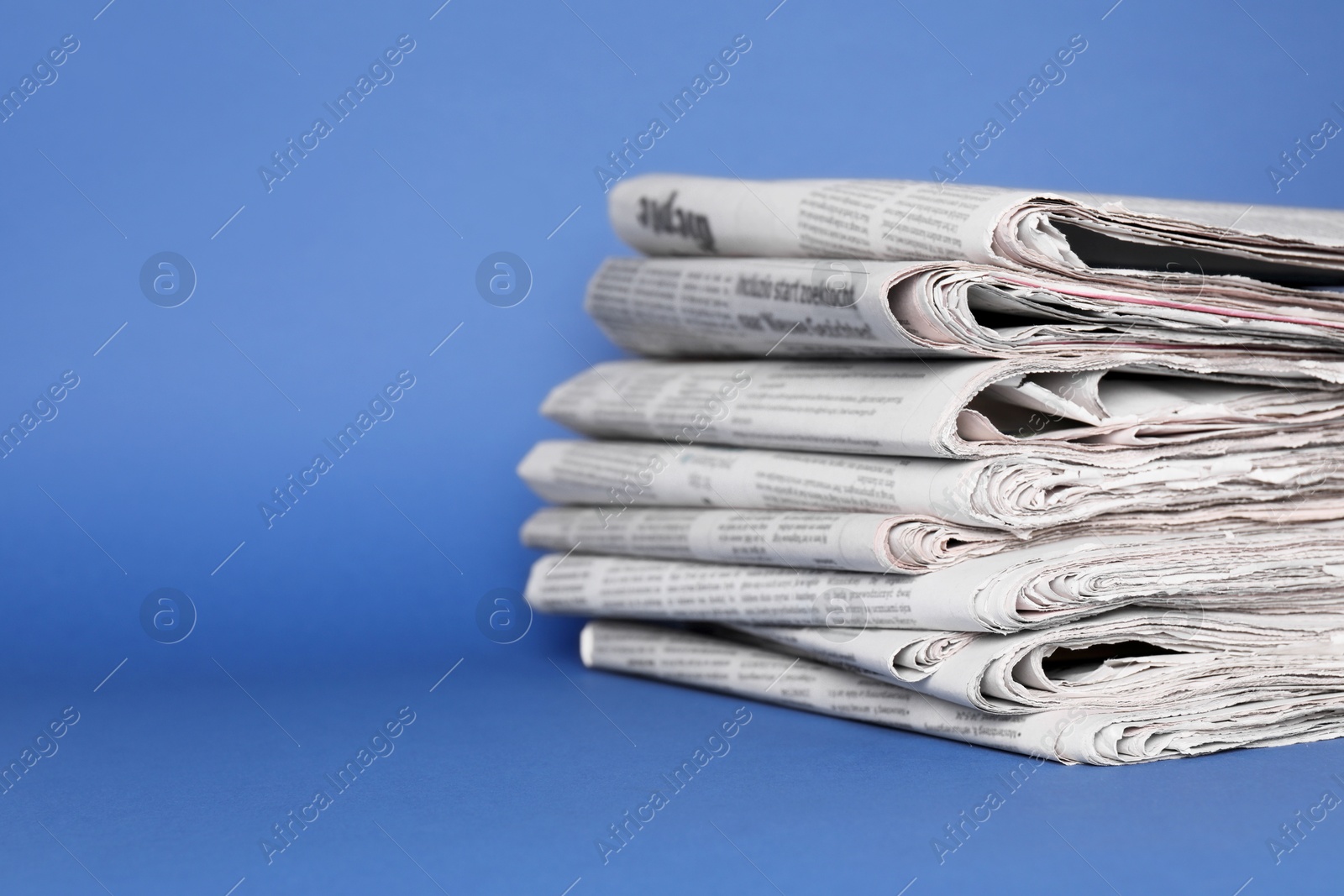 Photo of Stack of newspapers in different languages on blue background, space for text