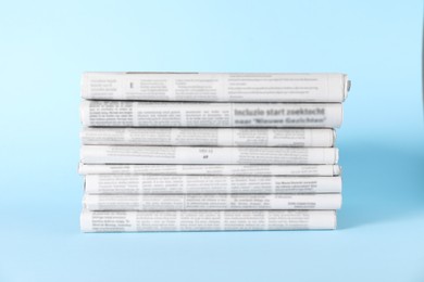 Photo of Stack of newspapers in different languages on light blue background