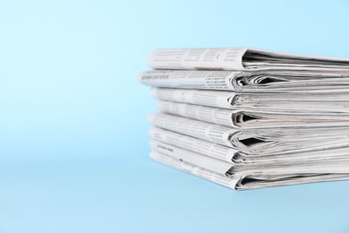 Photo of Stack of newspapers on light blue background, space for text