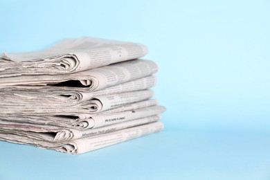 Photo of Stack of newspapers on light blue background, space for text