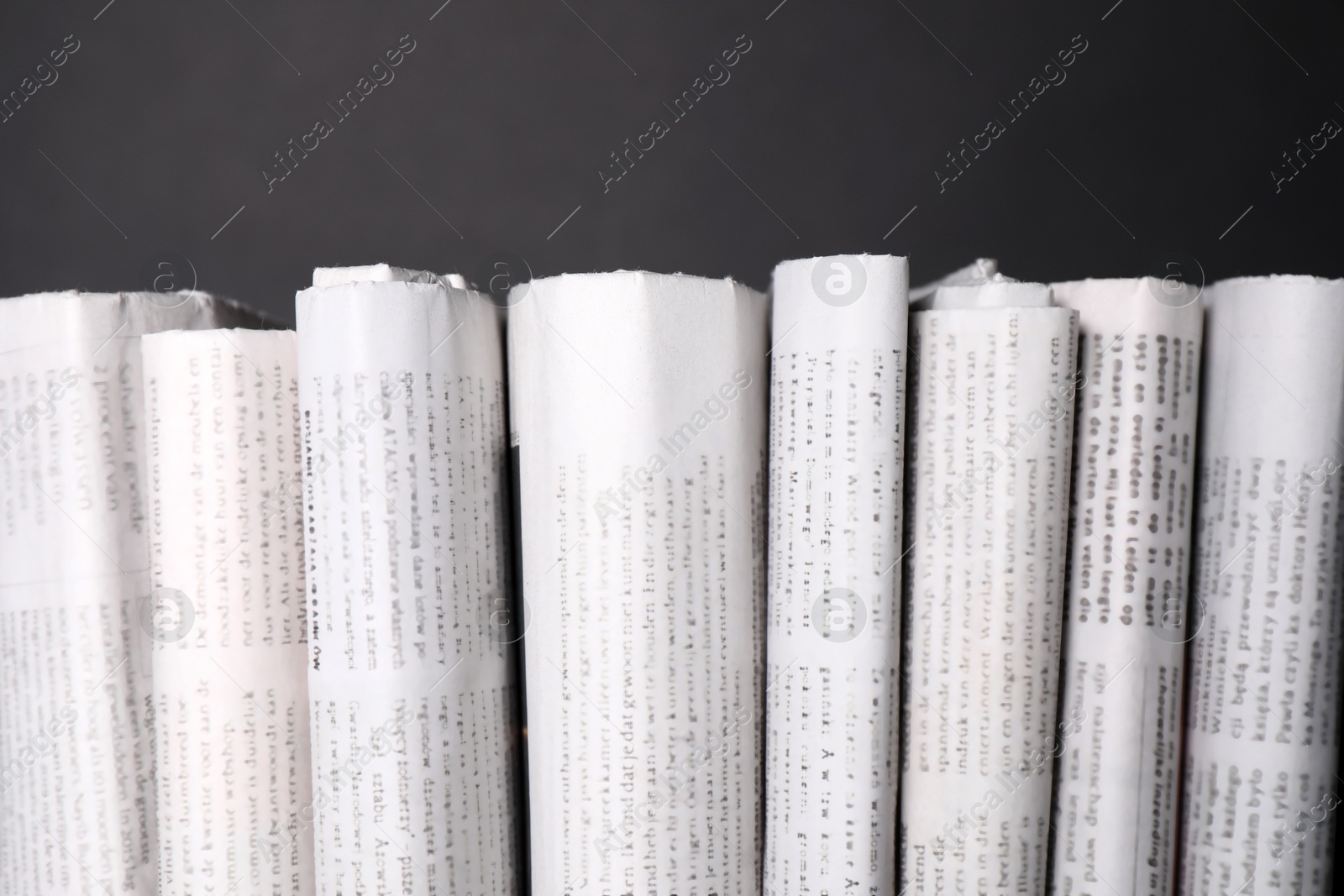 Photo of Many newspapers in different languages on grey background, closeup