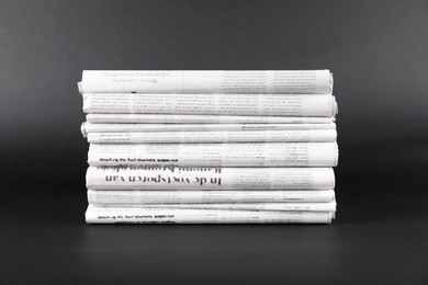 Photo of Stack of many newspapers in different languages on grey background