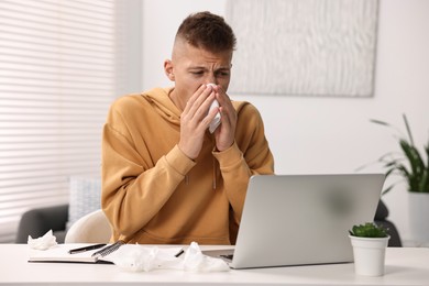 Photo of Cold symptom. Young man with runny nose at home