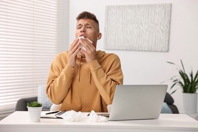 Photo of Cold symptom. Young man with runny nose at home