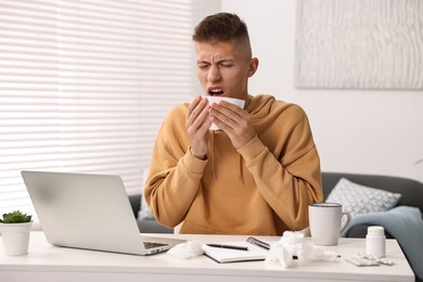 Photo of Cold symptom. Young man with runny nose at home