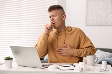 Cold symptom. Young man coughing at home