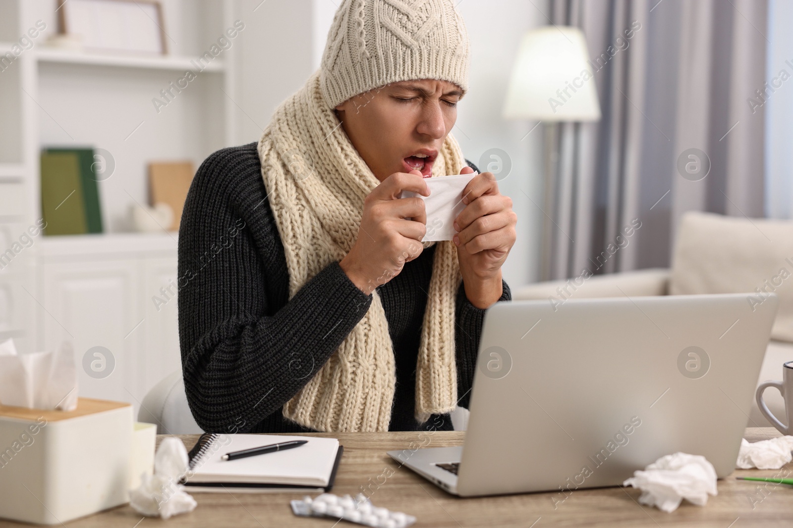 Photo of Cold symptom. Young man coughing at desk indoors