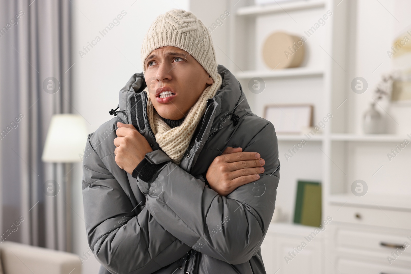 Photo of Cold symptom. Young man shivering from fever at home