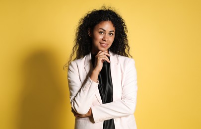 Beautiful woman in stylish jacket on yellow background