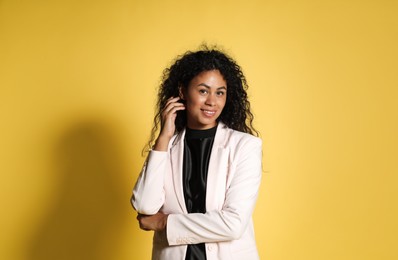 Beautiful woman in stylish jacket on yellow background