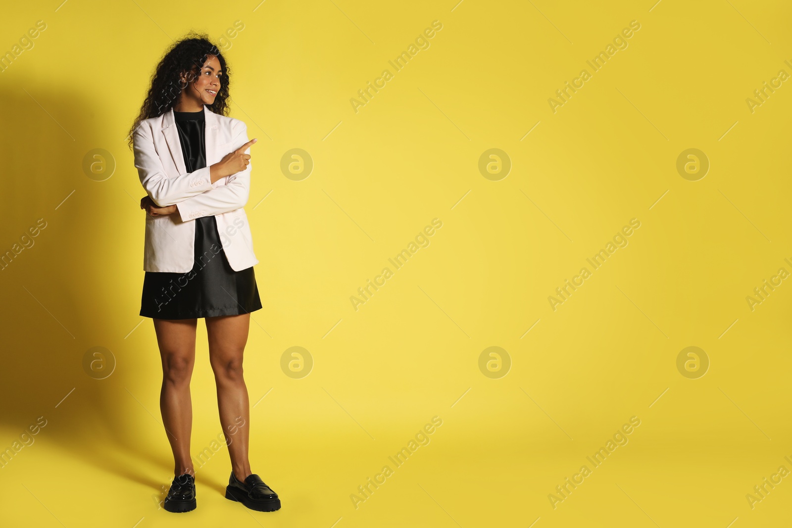 Photo of Beautiful woman in stylish jacket on yellow background, space for text