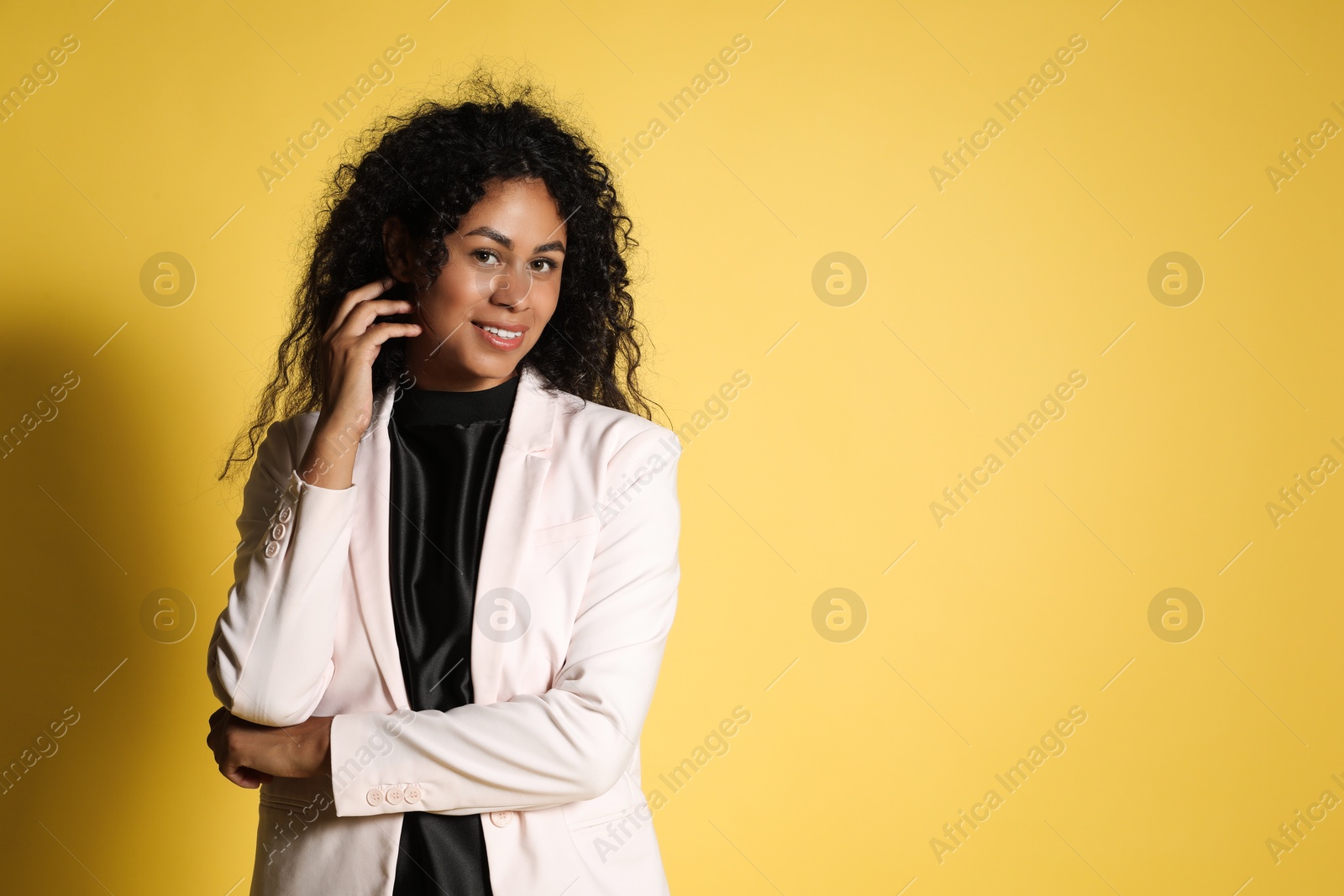 Photo of Beautiful woman in stylish jacket on yellow background, space for text