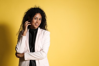 Beautiful woman in stylish jacket on yellow background, space for text