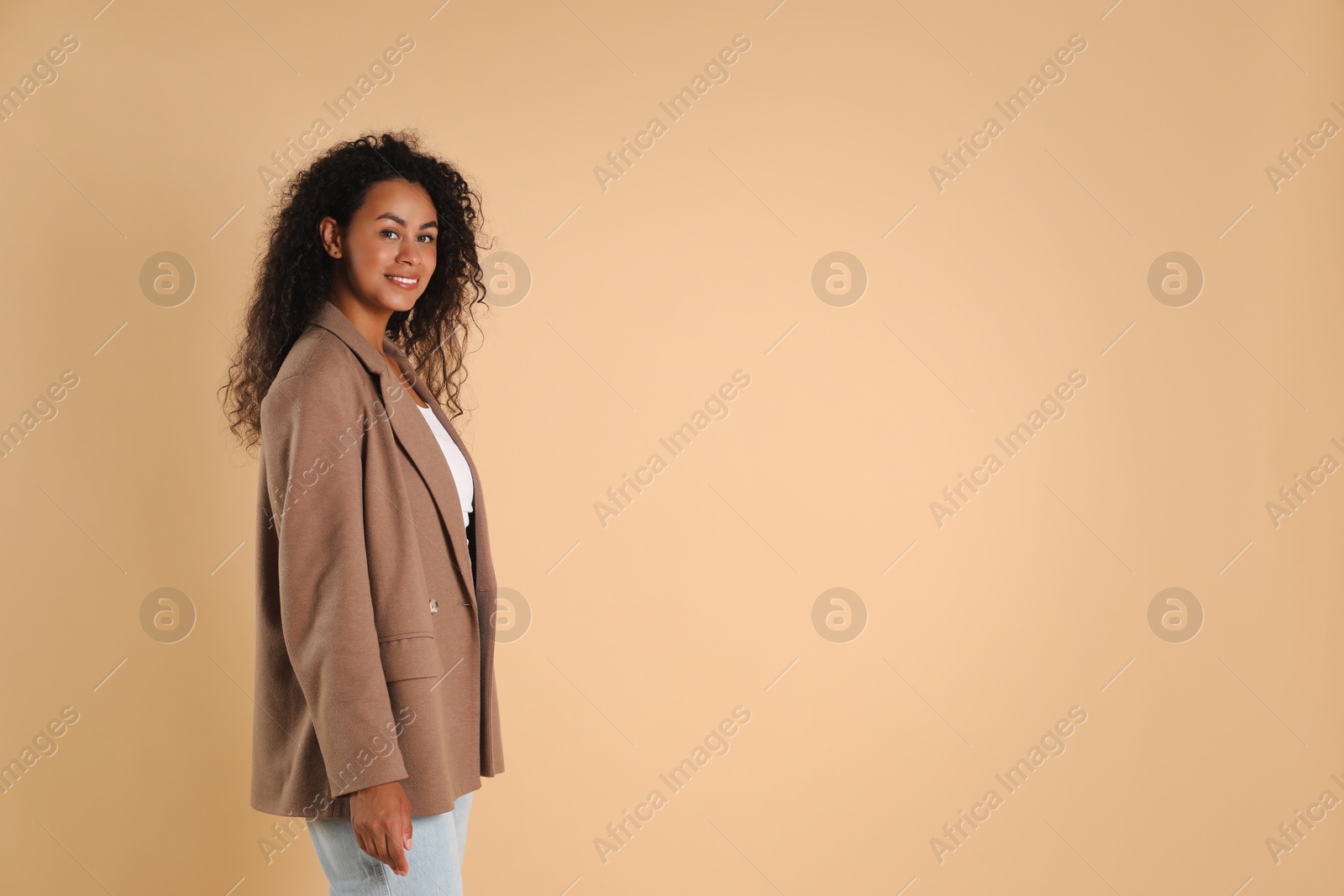 Photo of Beautiful woman in stylish jacket on beige background, space for text