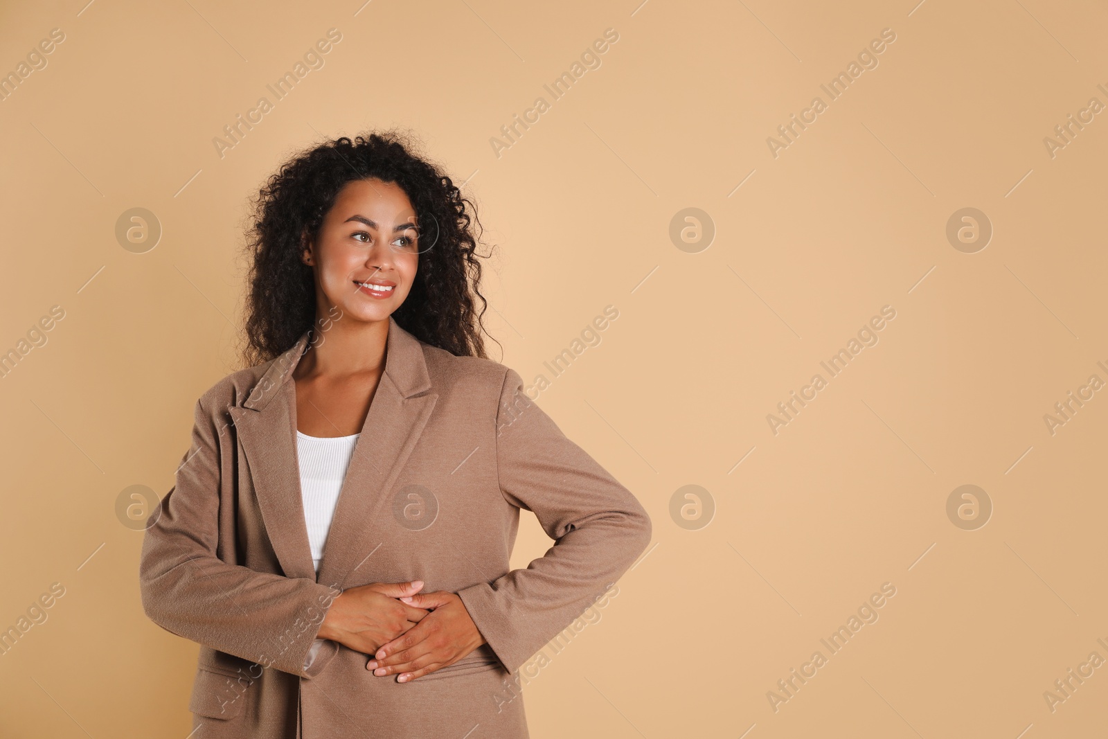 Photo of Beautiful woman in stylish jacket on beige background, space for text