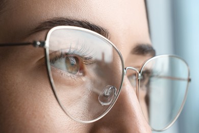 Photo of Closeup view of woman wearing eyeglasses on blurred background