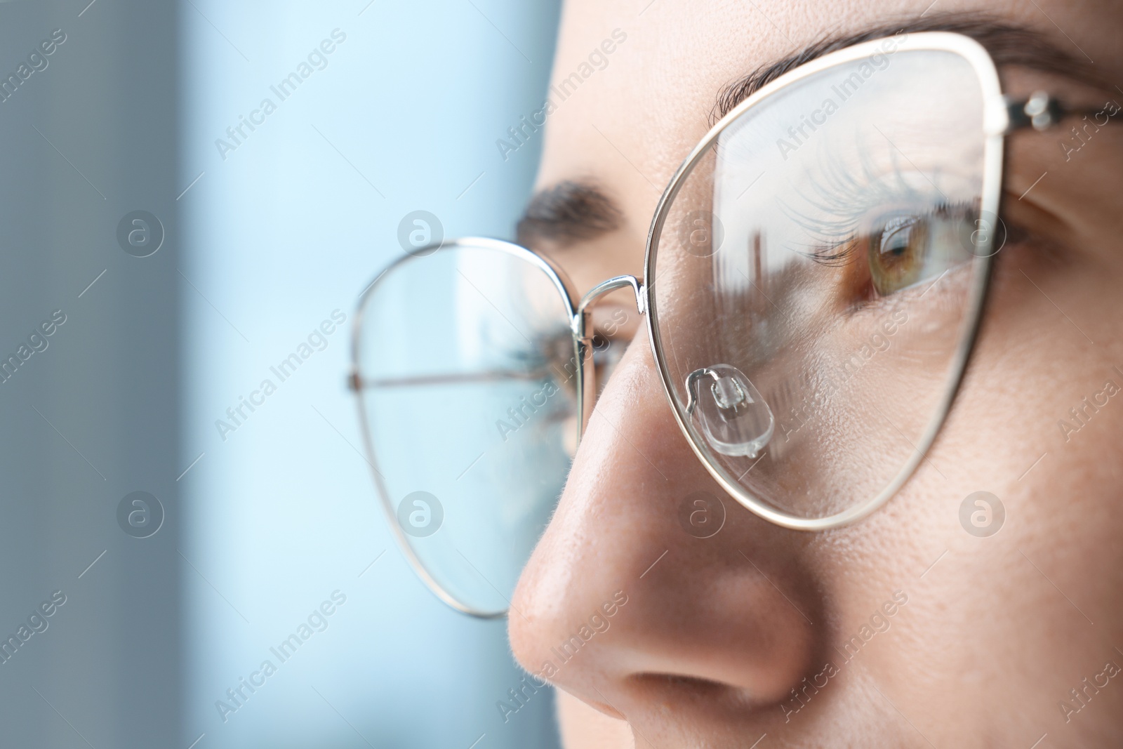 Photo of Closeup view of woman wearing eyeglasses on blurred background