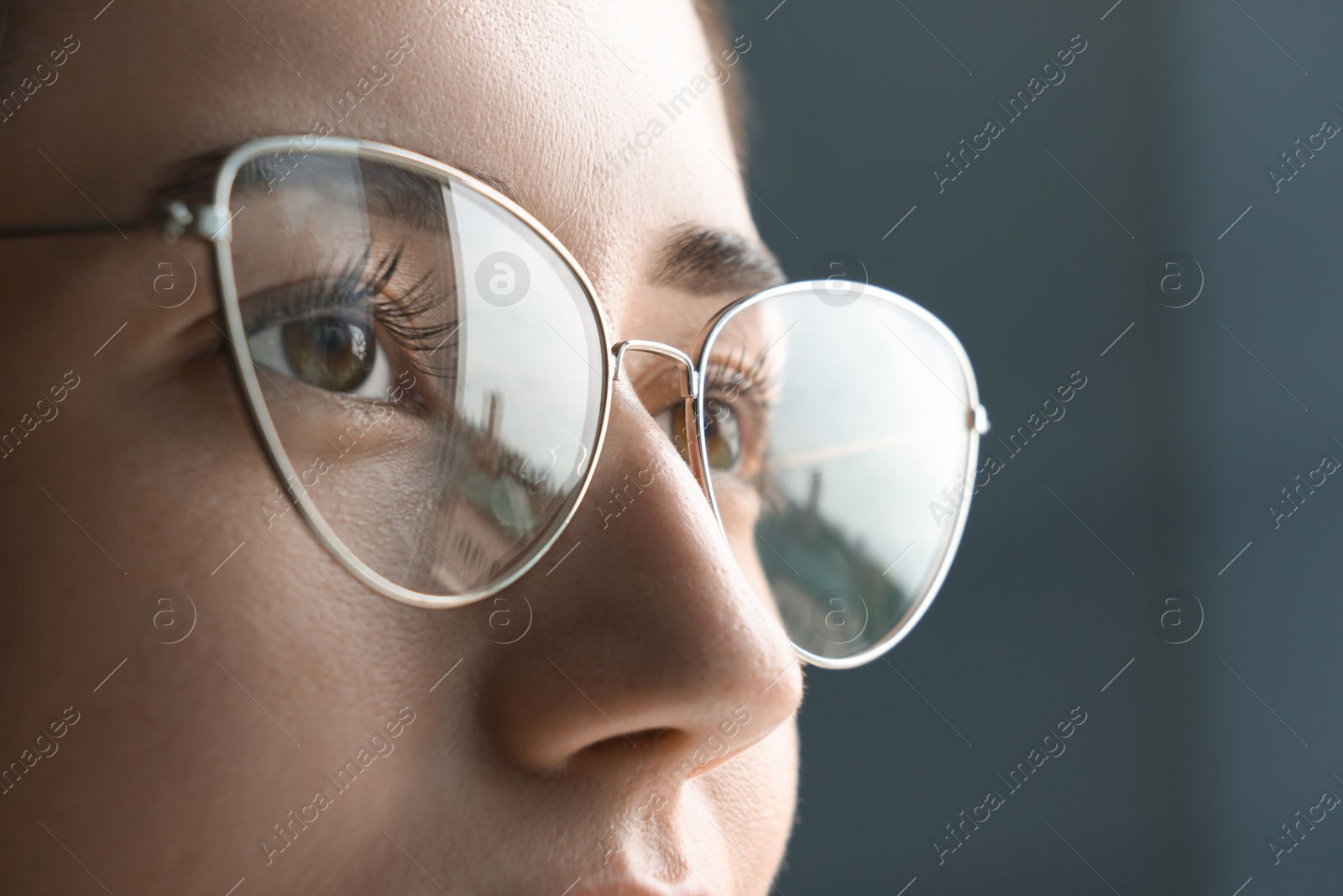 Photo of Closeup view of woman wearing eyeglasses on blurred background