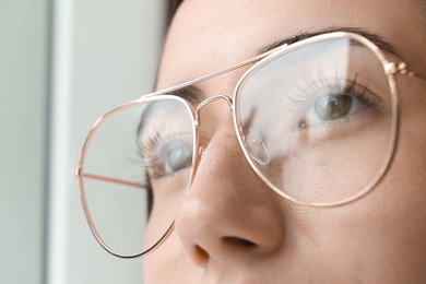 Closeup view of woman wearing eyeglasses on blurred background