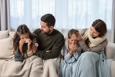 Cold symptom. Family suffering from fever on sofa at home