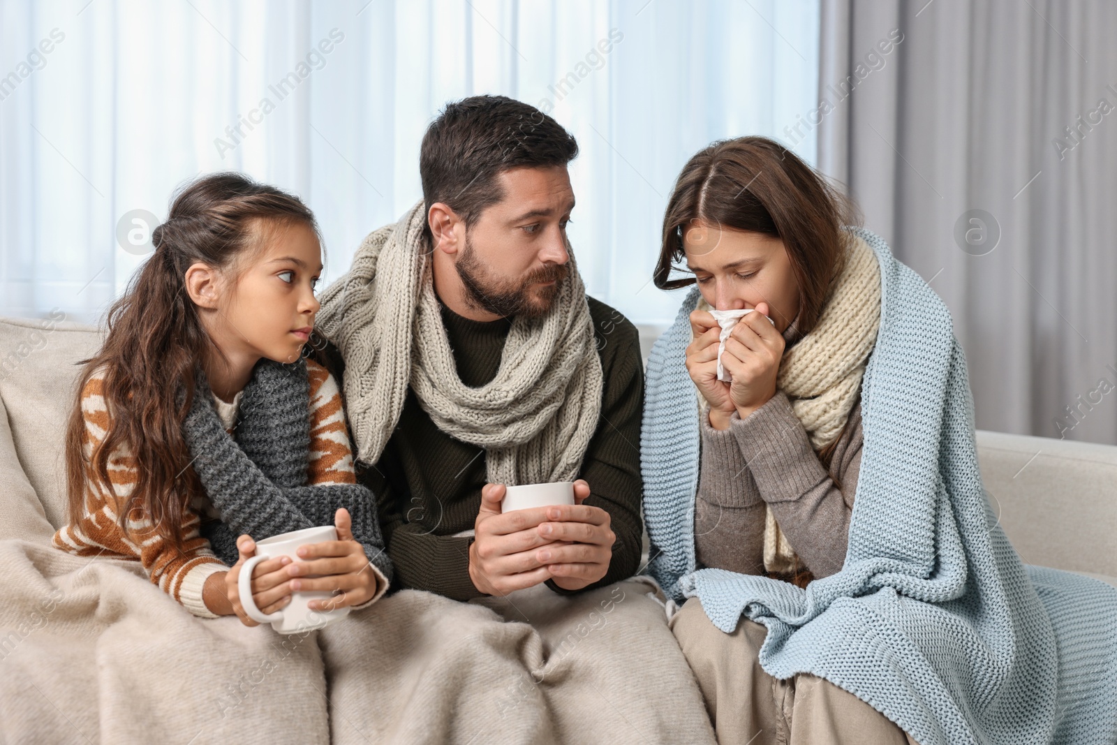 Photo of Cold symptom. Family suffering from fever on sofa at home