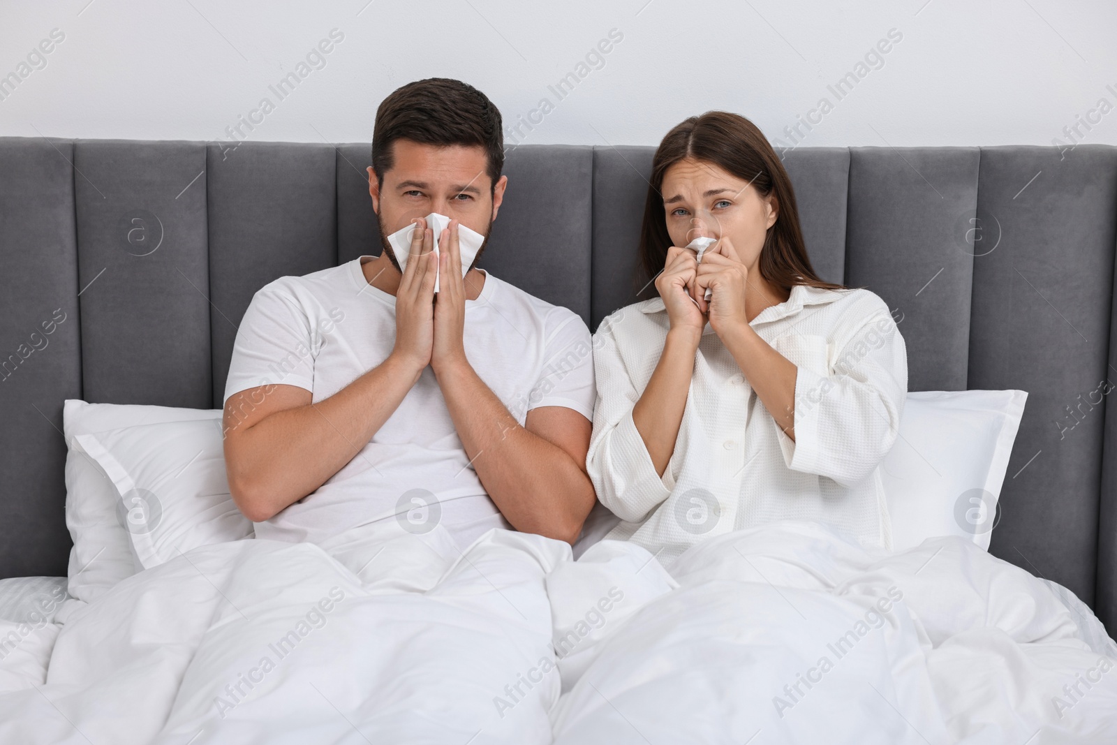 Photo of Cold symptom. Couple suffering from fever in bed at home