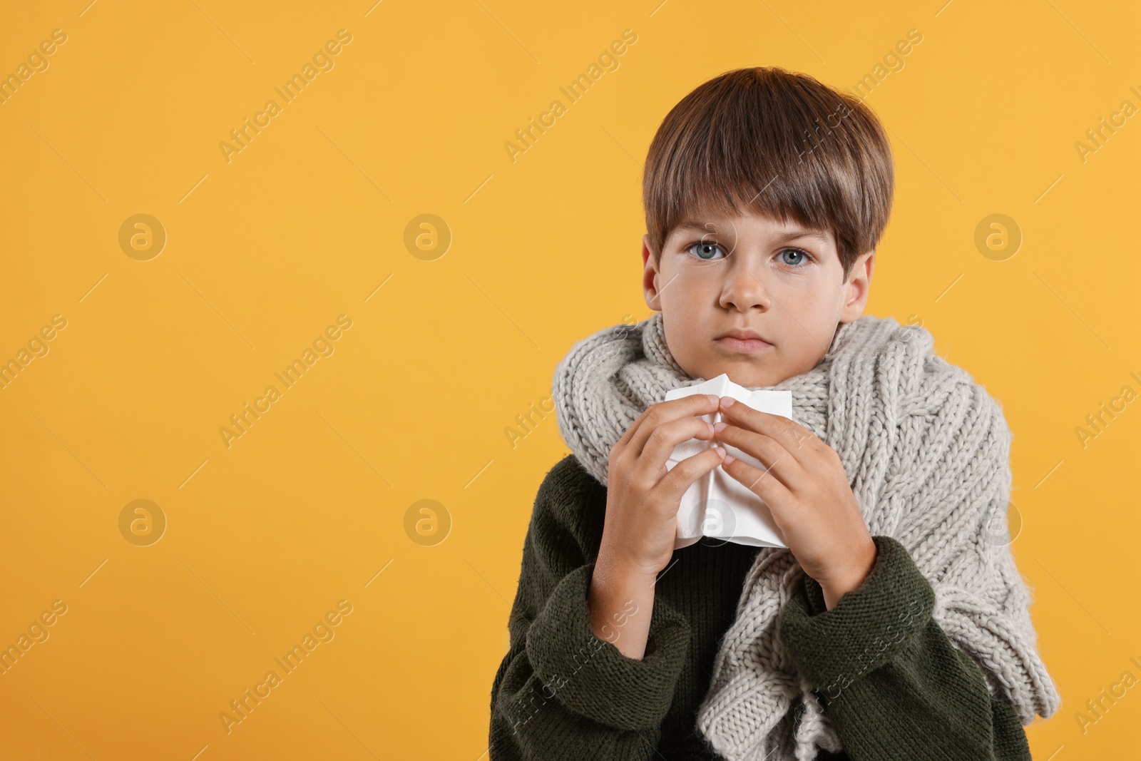 Photo of Cold symptom. Little boy with runny nose on orange background, space for text