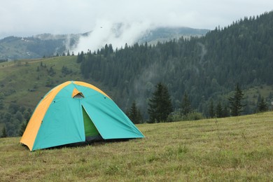 Photo of Camping tent on green grass in mountains, space for text