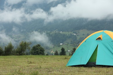 Camping tent on green grass in mountains, space for text