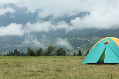 Camping tent on green grass in mountains, space for text