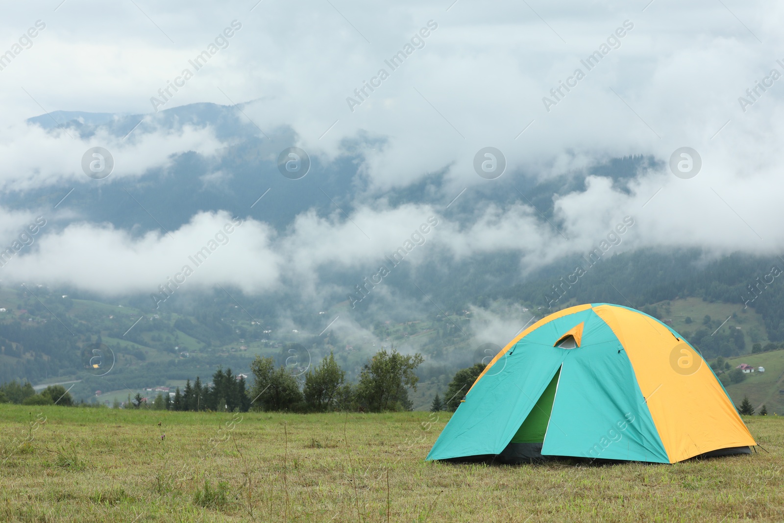 Photo of Camping tent on green grass in mountains, space for text