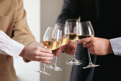 Photo of People clinking glasses of wine indoors, closeup