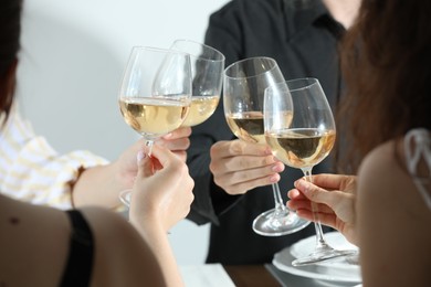 Photo of People clinking glasses of wine indoors, closeup