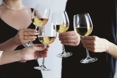 Photo of People clinking glasses of wine indoors, closeup