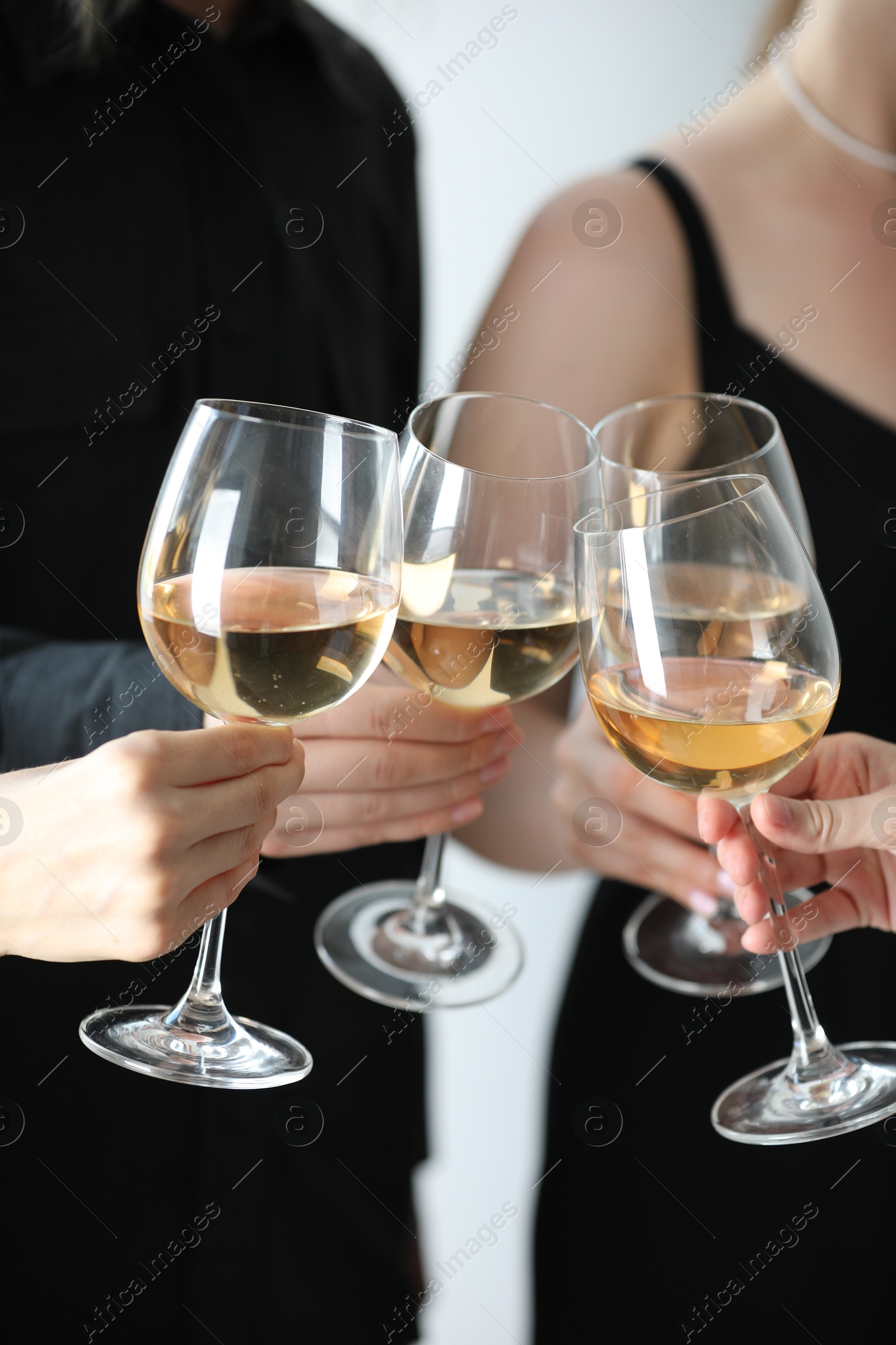 Photo of People clinking glasses of wine indoors, closeup