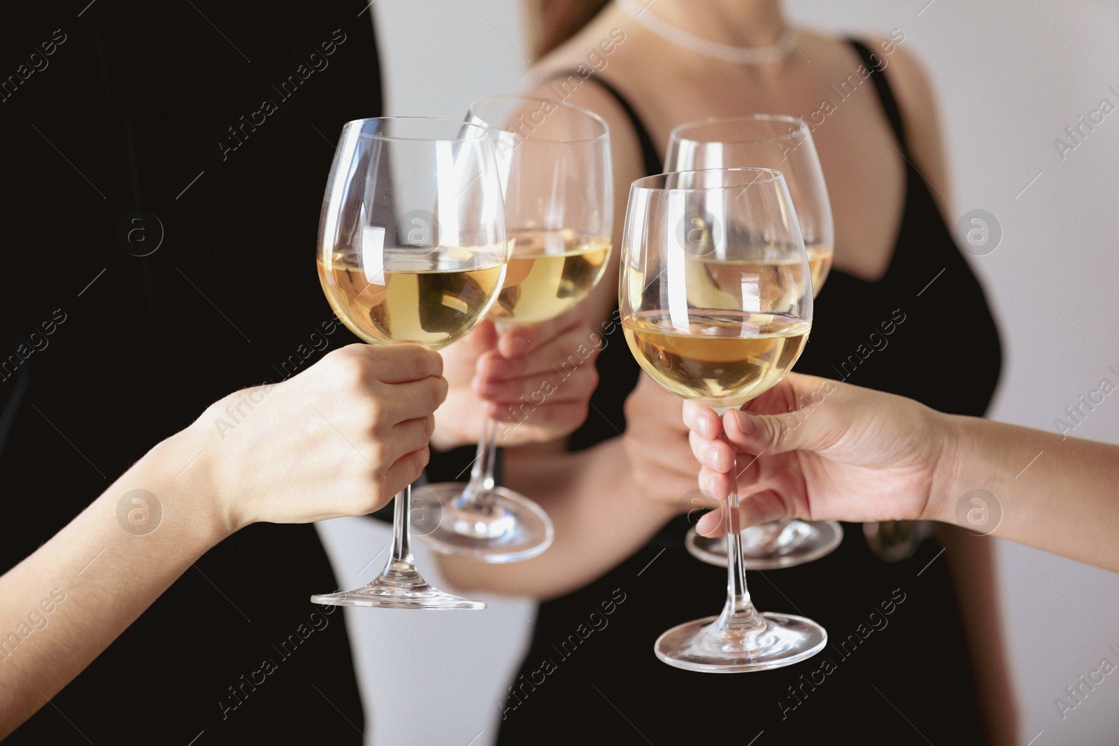 Photo of People clinking glasses of wine indoors, closeup