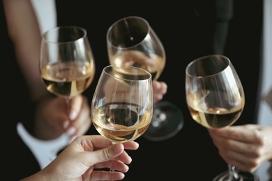 Photo of People clinking glasses of wine indoors, closeup