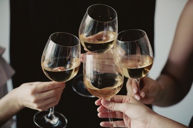 Photo of People clinking glasses of wine indoors, closeup